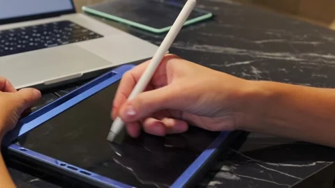 Close-up of a person drawing on a tablet using a stylus pen, working on digital Stock Footage 333581251