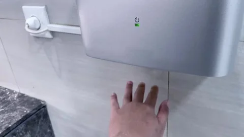 Close-up of a person drying their hands with an automatic electric hand dryer. Stock Footage 320503348