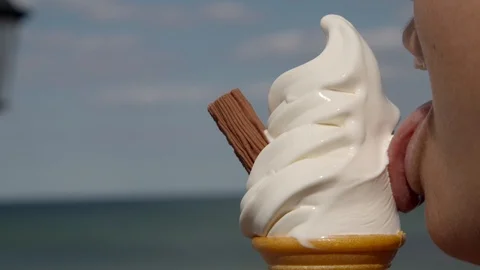 Close-up of a person eating an ice cream cone on a seaside pier Stock Footage