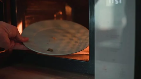 A close-up of a person examining an empty plate with crumbs in a microwave Stock Footage 339096659