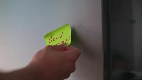 A close-up of a person examining a sticky note with the message "Good Morning" Stock Footage 339096528
