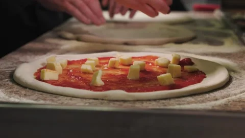 Close-up of a person hand adding chunks of cheese onto pizza base covered with Stock Footage 295779669