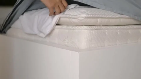 Close up of person hand fixing bed sheet and tucking edge into white bed fr.. Stock Footage 333156056