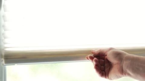 Close up of a person hand opening white window blinds on a bright day Vidéo 340159293