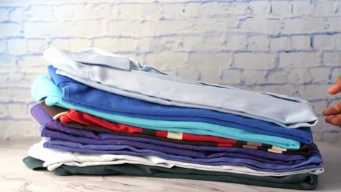 Close up of person hand picking up light blue shirt from stack of folded la.. Stock Footage 333030984