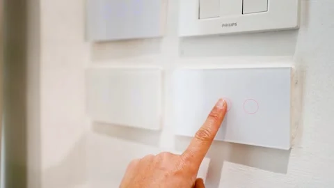 Close up of person hand touching modern smart light switch on white wall at.. Stock Footage 333320820