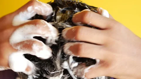 Close up of person hands massaging shampoo into thick dark hair on yellow b.. Stock Footage 333032291