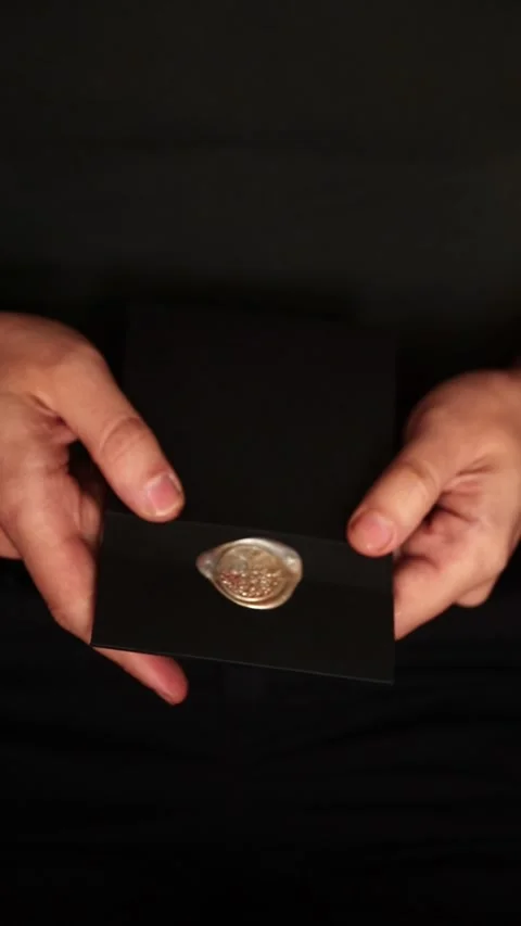Close-up of a person holding a black envelope sealed with a golden wax seal.. Stock Footage 345128319