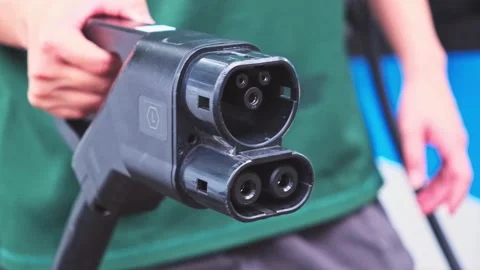 Close-up of a person holding a CCS EV charging plug, highlighting the connector Stock Footage 314770778