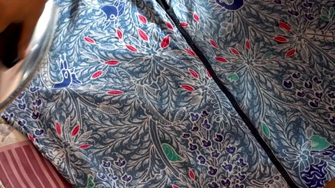 Close Up of Person Ironing Patterned Batik Fabric Shirt Stock Footage 343883743