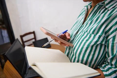Close-up of person multitasking with smartphone, notebook, and laptop at desk Fotos de archivo