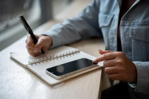 A close up of a person noting down in the notebook with left hand touching .. Foto stock