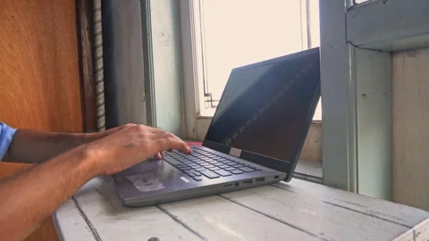 A close up of a person opening their dark grey portable computer on a brigh.. Stock Footage 345137700