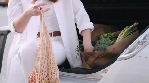 Close up of person placing fresh vegetables into a reusable canvas bag Video stock 336720261