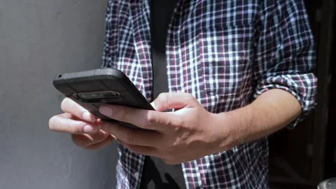 Close Up Of Person In Plaid Shirt Using Smartphone Video stock 339184954