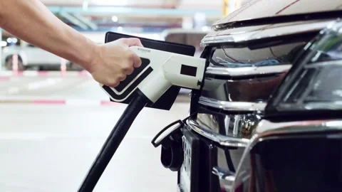 Close-up of a person plugging a charging cable into an electric vehicle Stock Footage 314770739