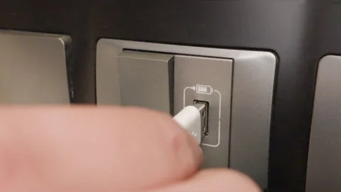 Close-up of a person plugging a white charging cable into a wall USB power port. Vídeos de archivo 344092358