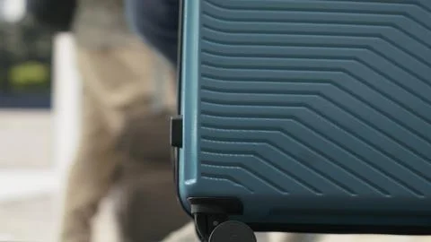 Close up of person pulling trolley baggage across bus station platform Stock Photos