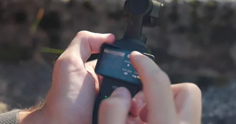 Close up of person selecting settings on DJI Osmo Pocket 3 miniature camera Video stock 316112784