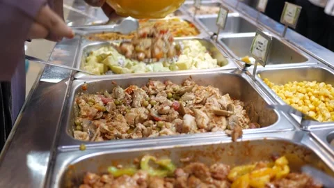Close up of person serving chicken with vegetables in buffet line with a spoo Stock Footage 332857918