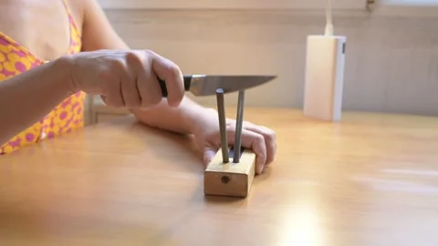 Close-up of a person sharpening a kitchen knife with a manual knife sharpener on Stock Footage 316119311