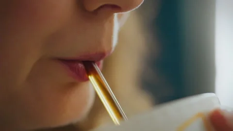Close-up of a person sipping a drink through a straw in a cozy indoor settin Stock Footage 288634761