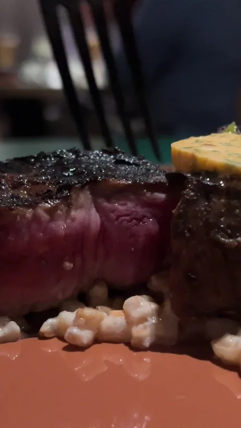Close-up of person slicing medium-rare steak on wooden cutting board. Sizzling Stock Footage 293022705