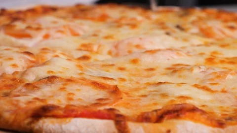 Close up of a person slicing a pizza into multiple slices with a pizza cutter Stock Footage 125981959