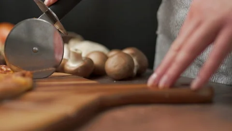 Close-up of a person slicing a pizza into multiple slices with a cutter. Stock Footage 137479521