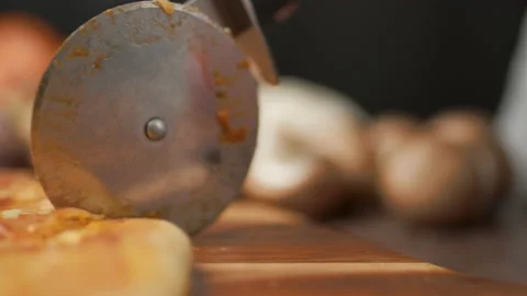 Close-up of a person slicing a pizza into multiple slices with a cutter. Stock Footage 137480165