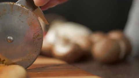 Close-up of a person slicing a pizza into multiple slices with a cutter. Stock Footage 137480330