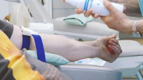 Close-up of a person squeezing a red stress ball while donating blood, with Stock Footage 331229729