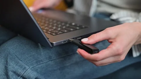 A close-up of a person trying to insert a USB drive into a laptop while sitting Stock Footage 338446291