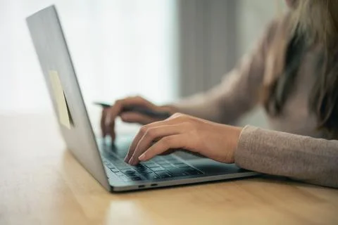 Close-up of a person typing on a laptop computer at a desk in a modern offi.. 스톡 사진