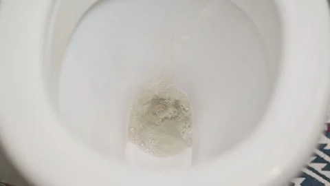 A close-up of a person urinating in a toilet while standing, with a stream of Stockbeeldmateriaal 337101336