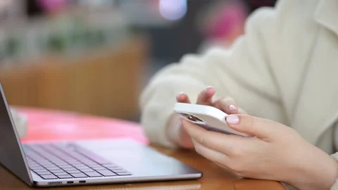 Close-up of person using smartphone and laptop on wooden table Stock Footage 345943494