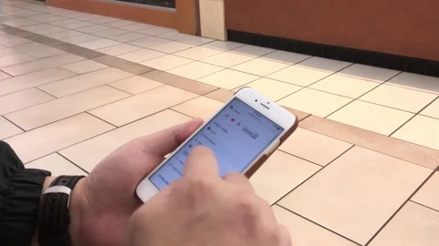Close-up of Person Using Smartphone with People Walking in Background at Pu.. Stock Footage 345832353