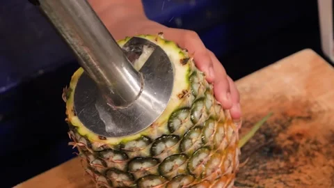 Close-Up of a Person Using a Stainless Steel Pineapple Corer and Slicer Tool on Stock Footage 345645634