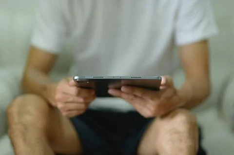 Close-up of a person using a tablet device while sitting casually indoors Stock Photos