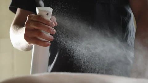 Close-up of a person using a white spray bottle to apply a fine mist over skin Stock Footage 329555004