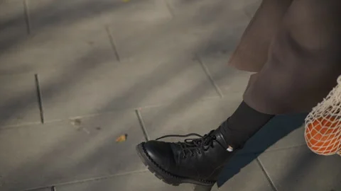 Close up of person walking on stone tile ground wearing black boots and carrying Stock Footage 346654768