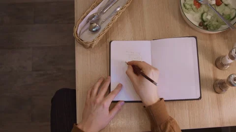 Close up of person writing mathematical equations in notebook with salad and Video stock 344871862