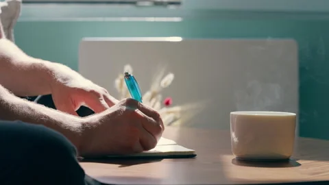 Close-Up of Person Writing in Notebook with Coffee Cup 库存影片 340017404