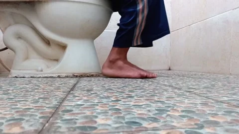 Close up of a person's feet on a tiled floor while sitting on a toilet. Stock Footage 335019682