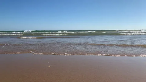 Close-up of a person's feet walking along the beach on the shore splashing wa Stockbeeldmateriaal 138402012