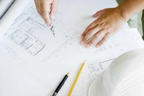 Close-up Of Person's Hand Drawing Plan On Blue Print with architect equipment Fotos de archivo