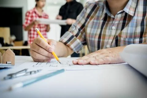 Close-up Of Person's Hand Drawing Plan On Blue Print with architect equipment Fotos de archivo