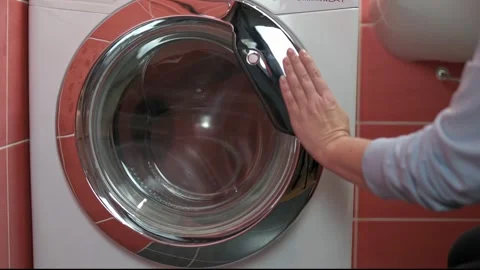 Close-up of persons hand gently closing door of front-loading washing machine in Stock Footage 291620938
