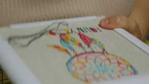 Close-up of a persons hand holding a hoop with colorful embroidery Stock Footage 312953656