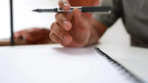 Close-up of a person's hand holding a pen above a blank notebook, ready to .. Stock Footage 320724923